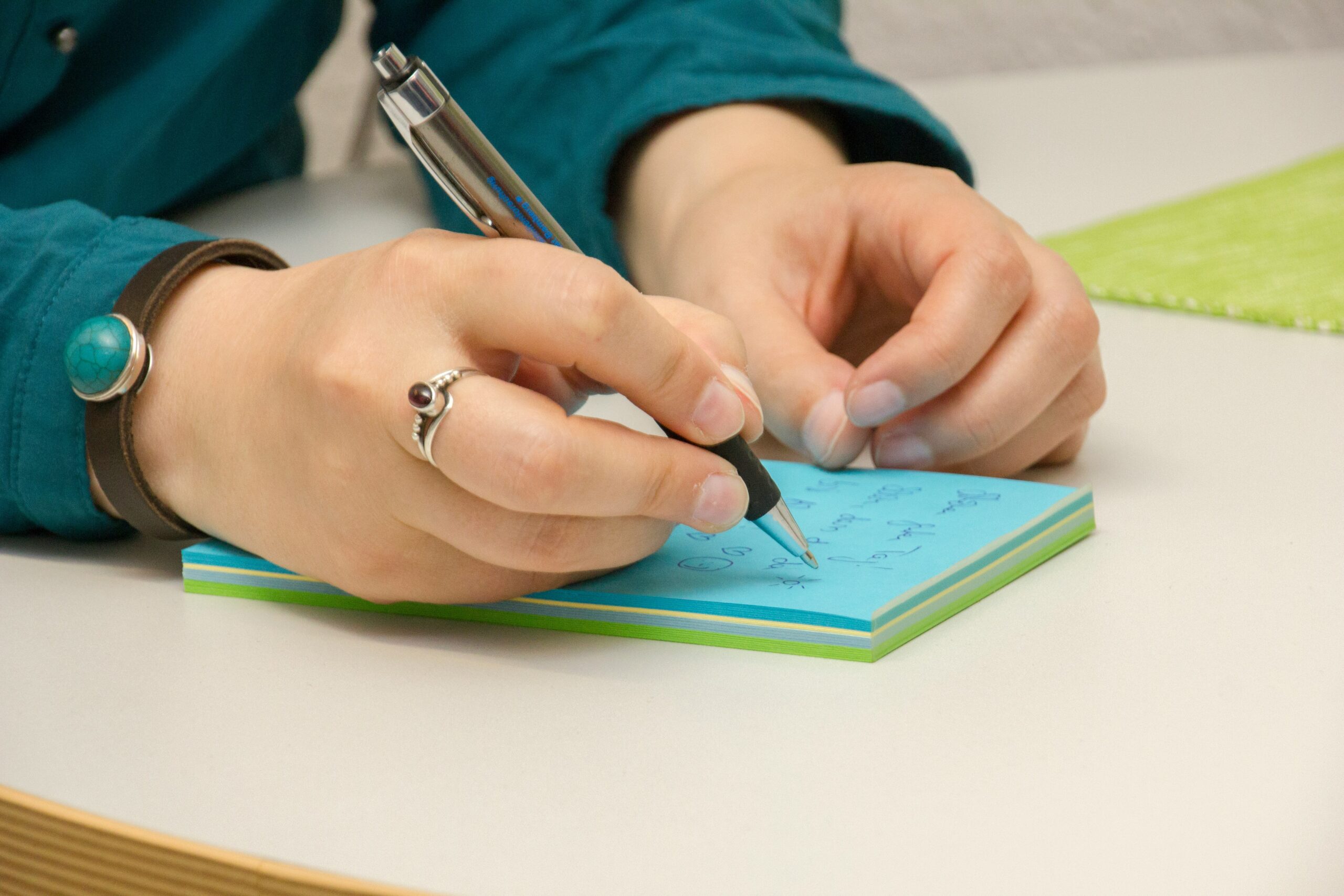 a person writing on a notepad with a pen